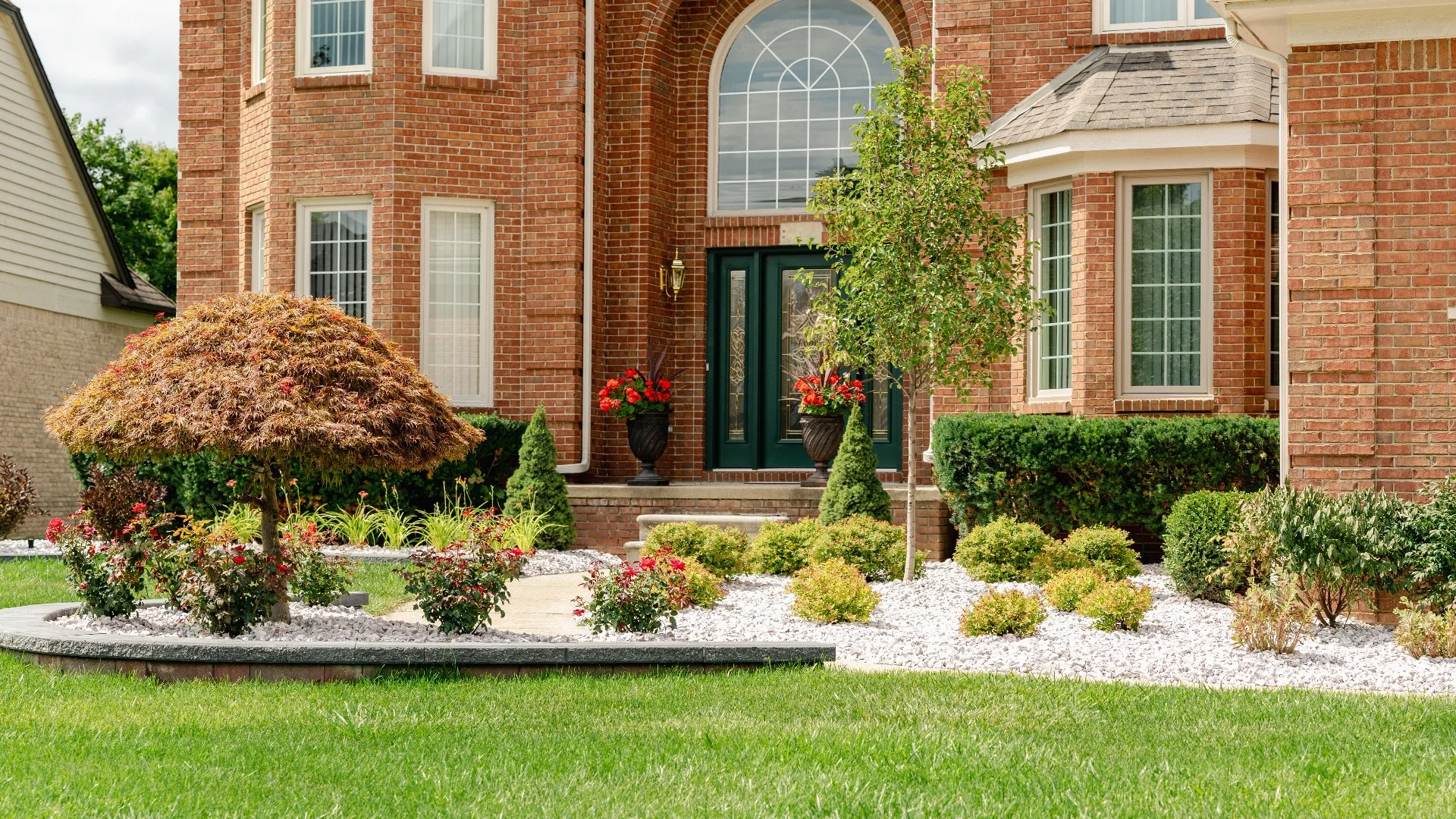 Beautiful front yard landscaping with shrubs, flowers, and a brick home in Macomb, MI.