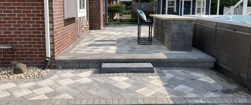 A backyard patio near a brick house in Macomb, MI, with an above-ground pool.