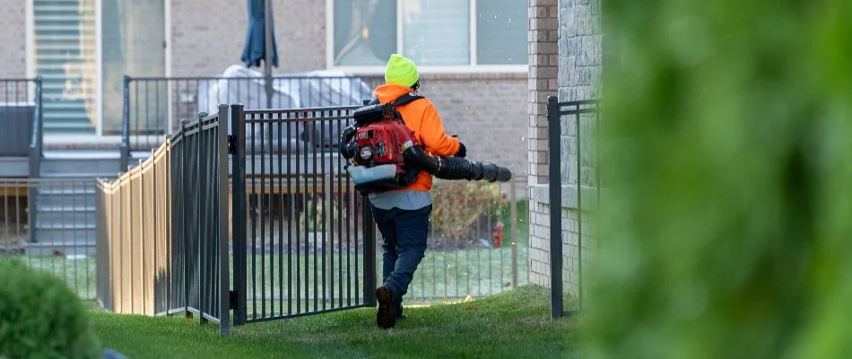 Crew using a leaf blower on a lawn in Macomb, MI, with leaves.
