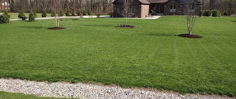 Large, green lawn in Macomb, MI, with mulch beds.