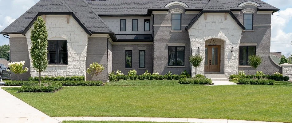 Large house in Macomb, MI, with a green front lawn and plants.