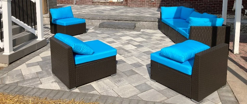 A paver patio in Macomb, MI, with blue chairs and a blue couch.