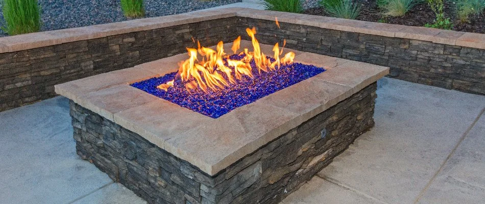 A rectangular fire pit in Macomb, MI, during the evening with a lit fire.