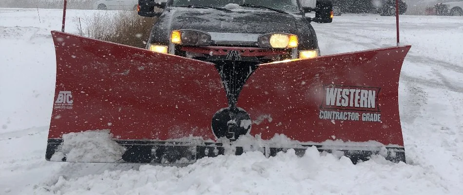 Red snow plow attached to a truck in Macomb, MI.