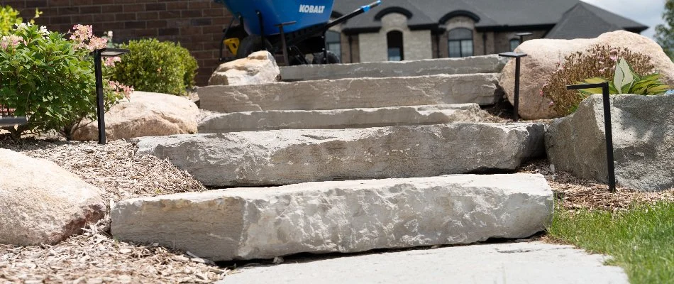 Outdoor steps in Washington, MI, with green shrubs and small boulders.