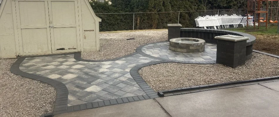 Paver patio in Clawson, MI, with a fire pit, seating wall, and shed.