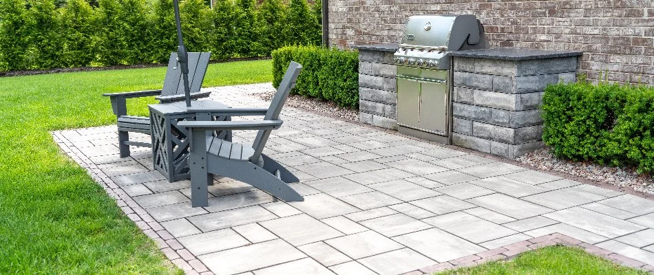 Paver patio in Fraser, MI, with an outdoor kitchen and chairs.