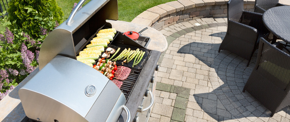Grill with food shown from a stone built outdoor kitchen near Shelby Township, MI.
