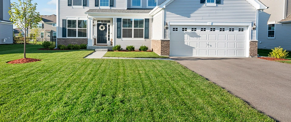 Our client's white home with a well maintained lawn and landscape in Sterling Heights, MI.