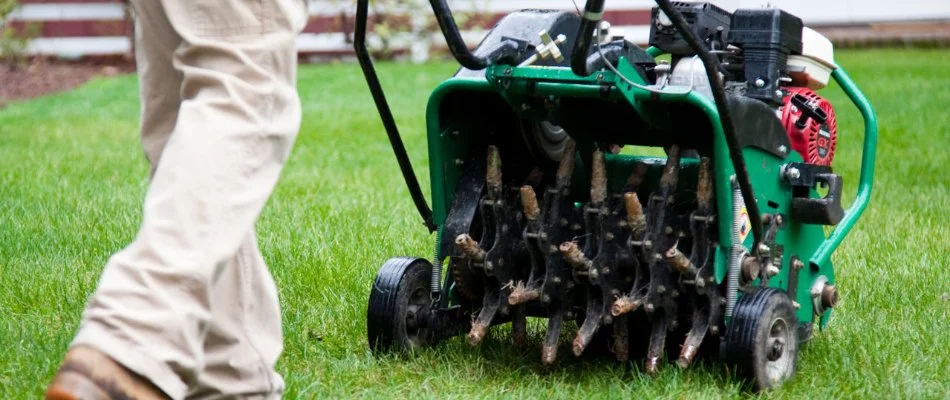 Worker pushing an aerator machine on a lawn in Macomb, MI.